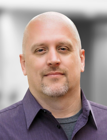 A portrait of Bob Mattson, a smiling man with a goatee, wearing a purple shirt, against a blurred background.