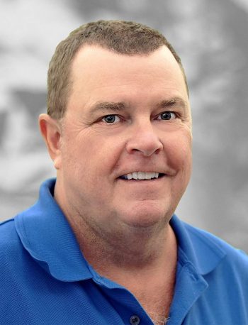 A portrait of Chris Todd, a smiling man wearing a blue polo shirt.