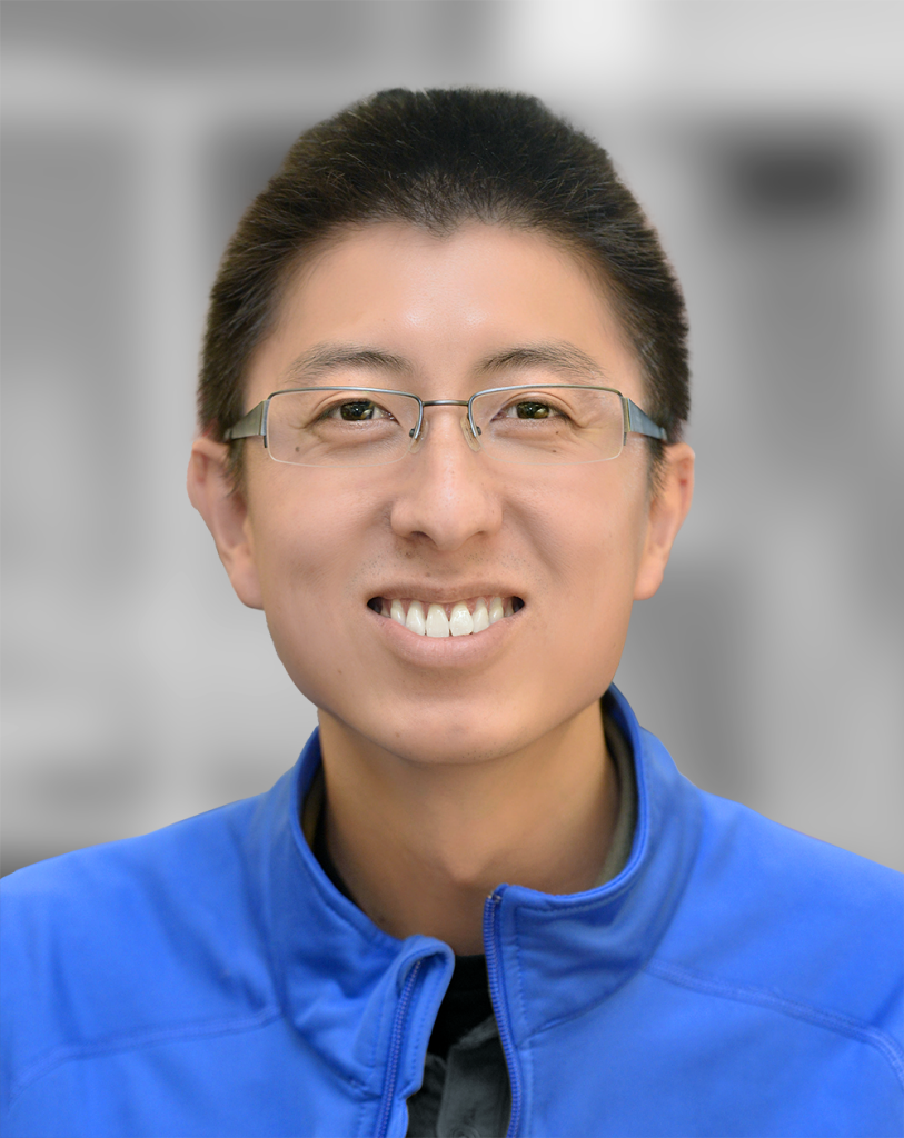 A portrait of Gabe Chow, a smiling man wearing glasses and a blue jacket with a blurred background.