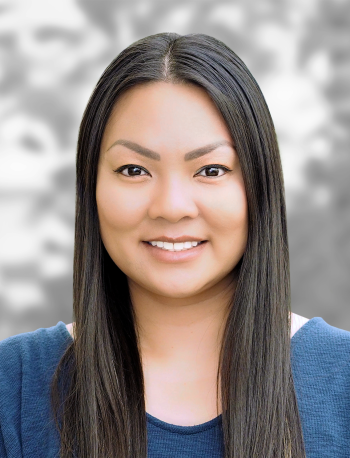 A portrait of Linh Vuong, a smiling woman with long straight hair against a gray background.