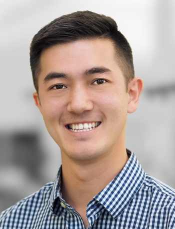 A portrait of Mitchell Parks, a smiling man with short hair wearing a checkered shirt.