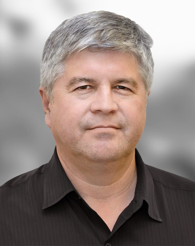 A portrait of Nick Lopez, a man with salt-and-pepper hair and a black shirt.