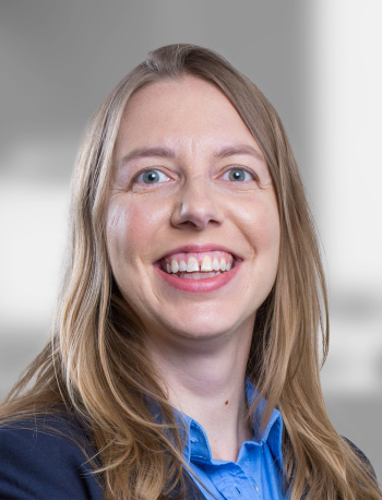 A portrait of Rachel Gerver, a smiling woman with long hair wearing a blue shirt and a blazer.