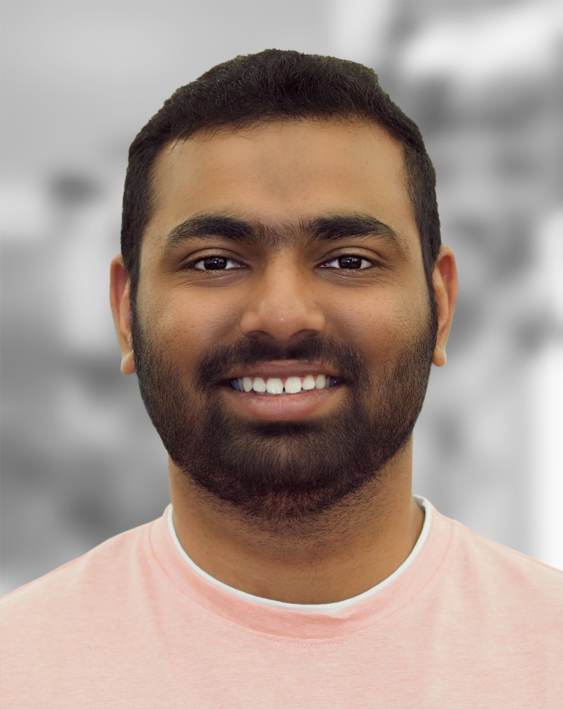 A portrait of Tanmay Kothale, a smiling man with a beard wearing a pink t-shirt against a blurred background.