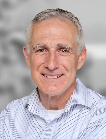 A portrait of Tobias Funk, a smiling man with grey hair wearing a striped shirt against a blurred background.