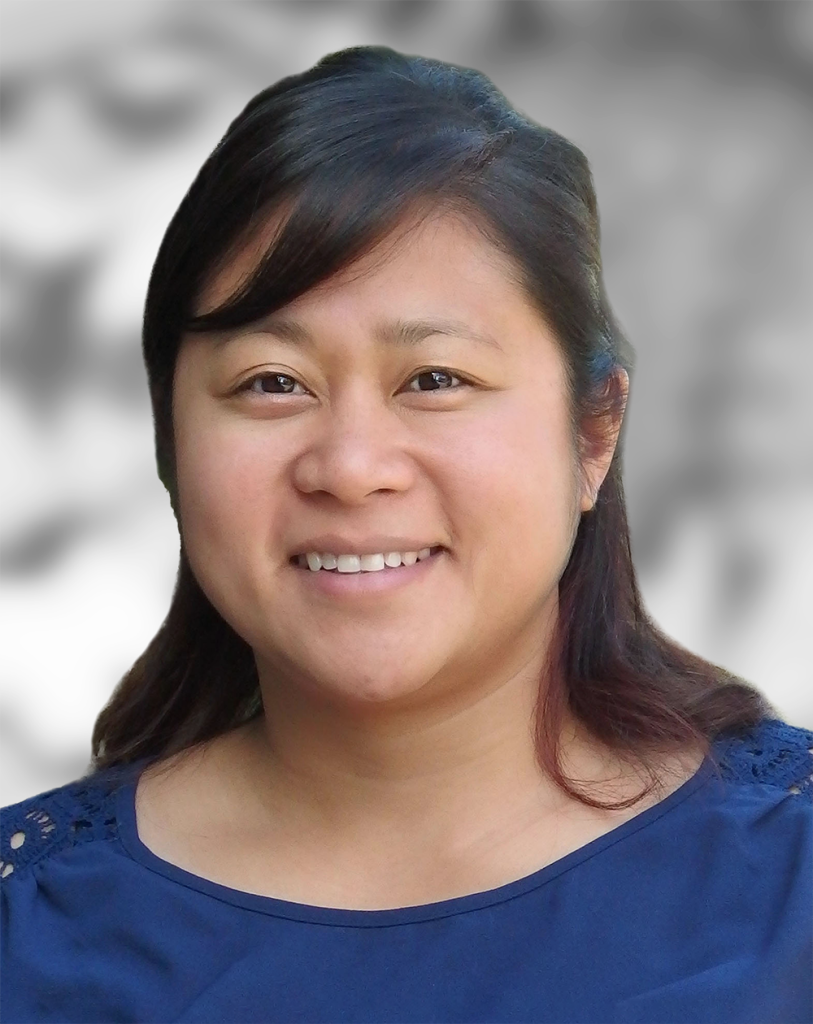 A portrait of Trisha Mitlo, a woman smiling at the camera with a blurred background.