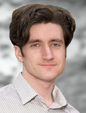 A portrait of Eric Bird, a smiling man wearing a patterned shirt against a blurred background.